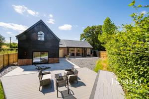 HaltonにあるHoneybee Barn - Stunning 4-Bed Rural Paradiseの木製デッキの椅子付き黒家