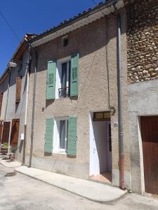 a building with green shuttered windows and a door at Agréable maison en Provence in Allemagne-en-Provence