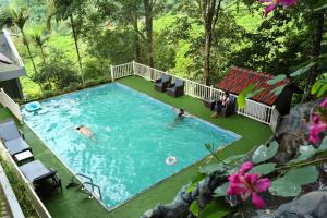 a swimming pool with two people in it at Chandys Windy Woods Munnar in Munnar