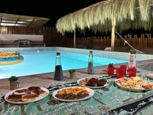 una mesa con platos de comida junto a una piscina en La casa de Diego, en Los Órganos