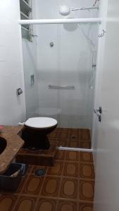 a bathroom with a toilet and a glass shower at Apto em Frente ao Mar - Prédio Redondo in Peruíbe +24 photos