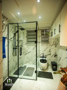 a bathroom with a glass shower with a toilet at Blessedlife Apartment in Kumasi