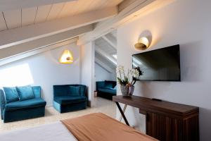 a room with a bed and two blue chairs and a television at Hotel Tiziano in Venice
