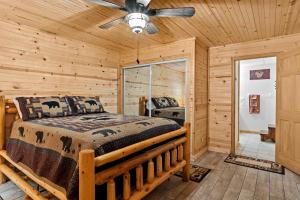 a log cabin bedroom with a bed and a ceiling fan at The Cabin Kingdom Hot tub Fire Pit in Blairsville