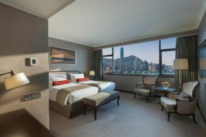 香港にあるマルコ ポーロ 香港 ホテルのベッドと大きな窓が備わるホテルルームです。
