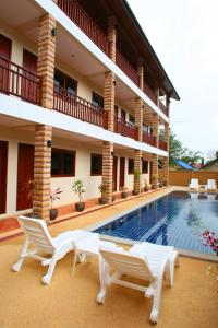 a resort with a swimming pool and chairs and a building at Hathai House in Lamai