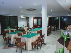 a dining room with green tables and chairs at Puri Mega Hotel in Jakarta