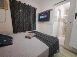 um quarto com uma cama e uma televisão na parede em Casa 2qts Vaga centro Arraial do cabo 5 min Praia em Arraial do Cabo