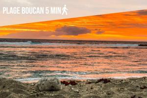 una roca en la playa con la puesta de sol en el fondo en La Rose Bohème Boucan Canot 2mn de la plage, en Saint-Paul