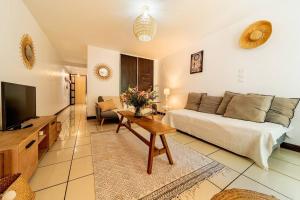 Una sala de estar con una cama y un televisor. en La Rose Bohème Boucan Canot 2mn de la plage, en Saint-Paul