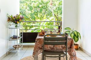 Una mesa en una habitación con vista a una ventana. en La Rose Bohème Boucan Canot 2mn de la plage, en Saint-Paul
