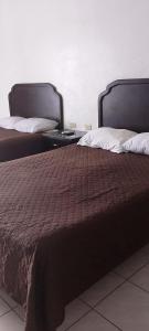 two beds sitting next to each other in a room at Hotel Estrella in Matamoros