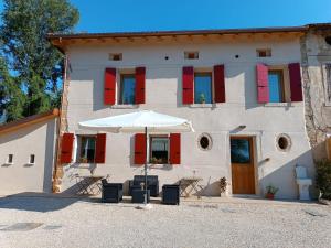 an umbrella in front of a building with red shutters at Agriturismo La Collina delle Api in Castelcucco
