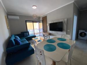 a living room with a table and blue chairs at VloraGB Apartment in Vlorë