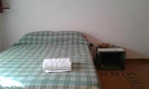 a bed with a green plaid blanket and a table at Habitacion serrana Stella Maris in Río Ceballos