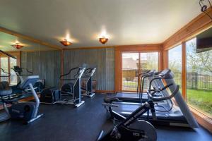 Un gimnasio con varias máquinas de correr en una habitación con ventanas. en Powder Peak Hideaway, en Eden