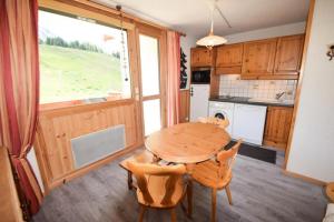 a kitchen with a wooden table and chairs and a window at Résidence Les Hameaux I - 2 Pièces 4 Pers - LES HAMEAUX 1 - 348H1 - PLAGNE VILLAGES MAE-9074 in La Plagne Tarentaise