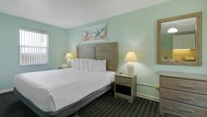 デイトナビーチにあるOcean Court Beachfront Hotelの大きな白いベッドと鏡のある寝室