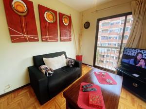 a living room with a black couch and a tv at Pampa Downtown Lodge in Mendoza