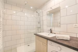 a white bathroom with a sink and a shower at Joli appartement à Caluire avec parking et jardin in Caluire-et-Cuire