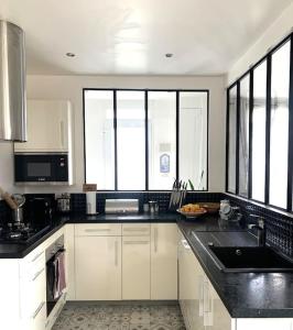 eine Küche mit weißen Schränken und schwarzen Arbeitsplatten in der Unterkunft Douceur de vivre in Neuilly-Plaisance