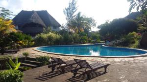 a swimming pool with two chairs in front of a house at Villa Fortuna Malindi in Malindi