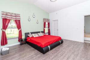a bedroom with a red bed and a window at Beautiful Fully Furnished 2-Bedroom Luxury Home in Kissimmee
