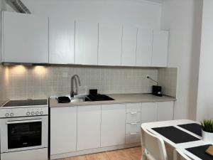 a kitchen with white cabinets and a sink at Peachy & Cozy in Serres +6 photos