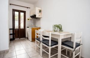 a white kitchen with a white table and chairs at Seafront & Sunsets Sigri House in Sígrion