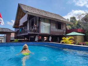a woman in a swimming pool in front of a house at I Guci Home in Munduk