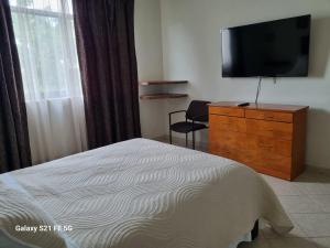 a bedroom with a bed and a dresser with a television at Delfin in Cruz de Huanacaxtle