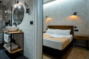 a bedroom with a bed and a sink and a mirror at Aparthotel Luz de Gades - Suites Spa Gym - Adults Only in Cádiz
