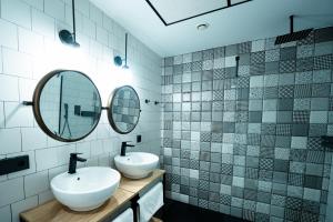 a bathroom with two sinks and two mirrors at Aparthotel Luz de Gades - Suites Spa Gym - Adults Only in Cádiz