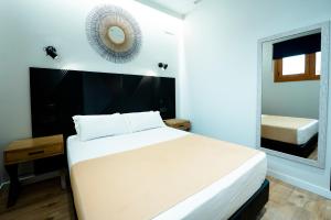 a bedroom with a large white bed and a mirror at Aparthotel Luz de Gades - Suites Spa Gym - Adults Only in Cádiz