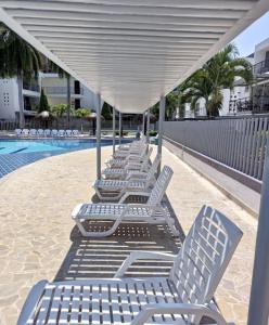a row of white lounge chairs under a canopy next to a pool at Apartasol Ciudadela SantaFe de Antioquia in Santa Fe de Antioquia +19 photos