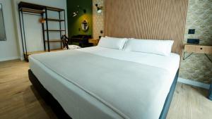 a large white bed in a room with a desk at Aparthotel Luz de Gades - Suites Spa Gym - Adults Only in Cádiz