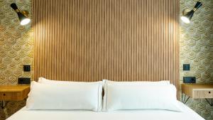 a bedroom with a bed with two white pillows at Aparthotel Luz de Gades - Suites Spa Gym - Adults Only in Cádiz