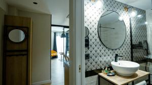 a bathroom with a sink and two mirrors on the wall at Aparthotel Luz de Gades - Suites Spa Gym - Adults Only in Cádiz