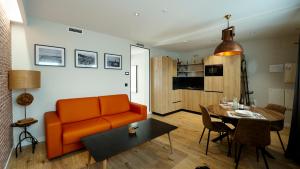 a living room with an orange couch and a table at Aparthotel Luz de Gades - Suites Spa Gym - Adults Only in Cádiz