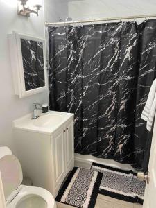 a bathroom with a black shower curtain and a toilet at Beautiful 4 bedroom 2 bathroom house in Gardena