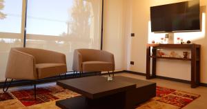 - un salon avec deux chaises et une télévision à écran plat dans l'établissement Hermoso Depto Nuevo 3D 2B y Litera Vista al Lago con Piscina Temperada , Jacuzzi, à Puerto Varas