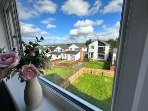 a vase of flowers sitting on a window sill with a view at Elite 3 bedroom family house with free parking in Newton Mearns