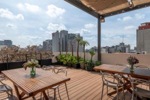 Un patio con mesas y sillas en un tejado. en Triver Coliving, en Ciudad de México
