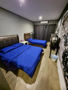 1 Schlafzimmer mit 2 Betten mit blauer Bettwäsche und einem Schreibtisch in der Unterkunft Tamara Resort Motel in Tioman Island