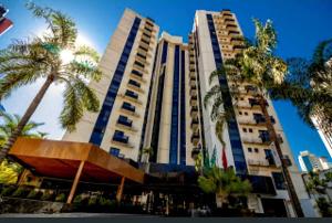 een hoog gebouw met palmbomen ervoor bij Studio Urbano Sun Square hotel in Goiânia