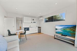 uma sala de estar branca com uma mesa e uma televisão em Guest House with Mountain Views em Wanaka