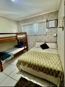 a bedroom with a bed and bunk beds in it at Acquamarine Hospedagem Apartamento c 2 quartos e suites para casal in Arraial do Cabo