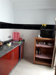 een keuken met rode kasten en een magnetron bij Le Joyau du Parc Tanger Vue Panoramique Parking Gratuit in Tanger