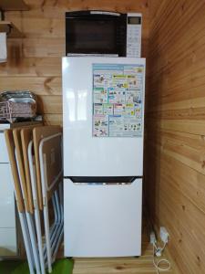 a white refrigerator with a microwave on top of it at Eco-friendly Log Cottage - be with nature in Furano