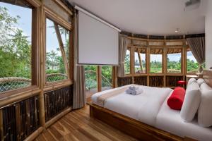 a bedroom with a bed and large windows at Clan Living - The Lovers Ubud Private Villas in Ubud